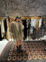 Ruana de lana merino color beige, tejida a mano con detalles de brillos y flecos.