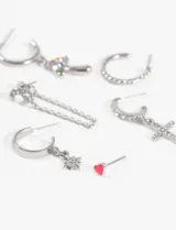 Set de caravanas doradas con diferentes dijes: un aro con dije de estrella, un aro con dije de hongo multicolor, un aro con dije de cruz con strass, un aro con textura trenzada, un aro con cadena y un botón rosa.