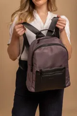 Mochila urbana color gris con detalles en cuero sintético negro. Cuenta con un compartimento principal amplio y un bolsillo frontal con cierre.