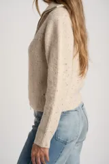 Cardigan de punto color beige melange con textura tweed, cuello alto y cierre frontal metálico. Corte ajustado al cuerpo y manga larga.