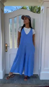 Mono largo de lino color beige, con breteles finos ajustables que se atan en la espalda, corte holgado y bolsillos laterales.