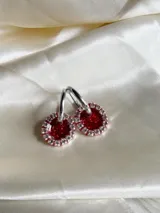 Par de aros colgantes con argolla de acero quirúrgico, dije circular de resina negra y borde de strass plateado.