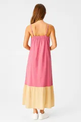 Vestido largo de lino color rosa y amarillo, con breteles finos, corte holgado, bolsillos laterales y falda con volantes.