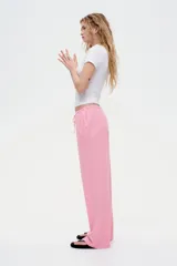 Pantalón de tiro bajo color rosa, confeccionado en tejido liviano con lino en la trama. Presenta elástico revestido y cordón para ajustar en la cintura, bolsillos al bies y piernas rectas.