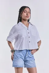 Camisa blanca de mangas cortas con dobladillo, cuello clásico, cierre frontal con botones y dos bolsillos frontales con solapa.