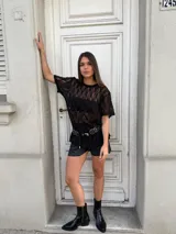 Remerón negro de encaje con mangas cortas, cuello redondo y corte holgado. Incluye un cinturón con apliques metálicos.
