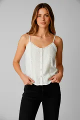 Musculosa blanca de algodón con breteles finos, escote en V con puntilla y cierre frontal con botones. Presenta detalle de pinzas verticales en el frente.