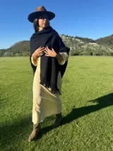 Ruana color beige confeccionada en lana merino con flecos en el borde inferior.