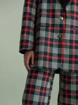 Pantalón de corte ancho y tiro alto con estampado de cuadros en tonos negro, rojo y verde, con cierre y botones invisibles en el interior.