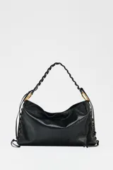 Bolso de hombro alargado color negro, con detalle de pasados metálicos en los laterales y asa trenzada. Tiene doble bolsillo interior con cremallera y cierre mediante botón imantado.