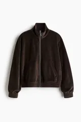 Campera corta de velour marrón oscuro, con cuello elevado, cierre frontal y bolsillos insertados al bies. Presenta elástico fruncido en puños y bajo.