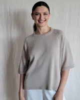 Sweater color beige de tejido de punto con mangas cortas y cuello redondo.