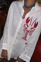 Camisa blanca de lino con bordado de langosta roja en el frente.