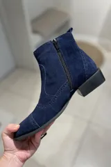 Bota corta de cuero vacuno color negro charol, con elástico lateral, punta fina y detalles de calado.