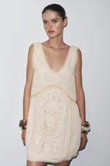 Vestido corto color crudo con bordados a tono, escote redondo y sisas amplias.