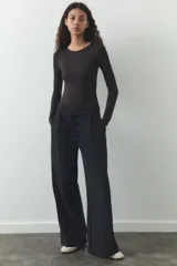 Pantalón negro de tiro alto, corte ancho y largo midi. Incluye bolsillos delanteros, pinzas y cinturón de la misma tela.