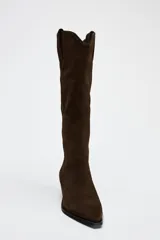 Bota alta de caña alta color marrón chocolate, de serraje con puntera fina y taco bajo.