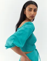 Top turquesa con escote cuadrado, mangas abullonadas y cuerpo fruncido.