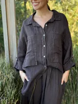 Camisa oversize rosada de lino, con cuello clásico, cierre frontal con botones, dos bolsillos de parche en el pecho y mangas largas con puños abotonados.