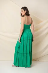 Vestido largo de fiesta color verde esmeralda, confeccionado en seda natural. Presenta escote en V con corsé drapeado, breteles finos y falda con volados.