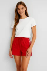 Short rojo de lino y viscosa con cintura elastizada y cordón de ajuste. Presenta dos líneas verticales blancas a los costados.