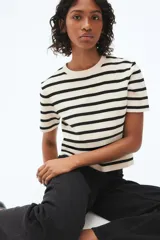 Remera de punto fino color crema con rayas horizontales negras, de manga corta y cuello redondo.