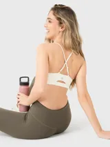 Top deportivo de lycra gris con tirantes finos cruzados en la espalda y almohadillas removibles.