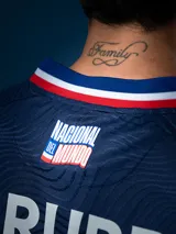 Camiseta de fútbol Umbro del Club Nacional de Football, modelo Away 2025. Diseño azul con detalles en blanco y rojo en cuello y mangas. Incluye logo de Umbro, escudo del club y sponsor Antel en el frente.