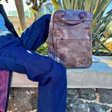 Mochila de cuero color marrón claro con múltiples bolsillos y cierres.