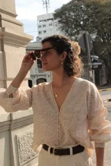 Camisa estampada con flores pequeñas, escote en V con detalle de puntilla, mangas largas abullonadas y cierre frontal con botones.