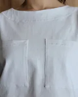 Remera negra con cuello redondo y mangas cortas, con detalle de pespuntes blancos en cuello, mangas, bolsillos frontales y ruedo.