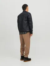 Chaqueta de cuero sintético negra, de corte entallado, con cuello mao, cierre frontal con cremallera, bolsillos laterales y en el pecho con cremallera, y detalles acolchados en hombros y mangas.
