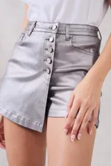 Skort de poliéster color plata, con cierre frontal de botones y diseño asimétrico.