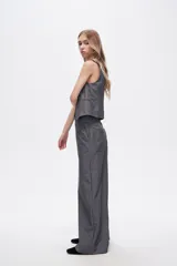 Pantalón gris de poliéster, corte ancho y tiro alto, con bolsillos laterales.