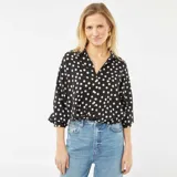 Blusa negra con lunares blancos, de corte holgado, cuello camisero y mangas 3/4.