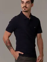 Chomba azul marino Calvin Klein de corte slim fit, manga corta y cuello polo con tapeta de dos botones. Logo de la marca bordado en el pecho.