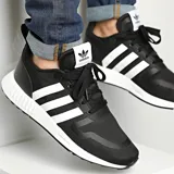 Championes Adidas Multix negros con las tres tiras blancas, suela blanca y detalles en blanco en la lengüeta y el talón.