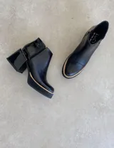 Botas cortas negras con textura de piel de serpiente y detalles en charol.