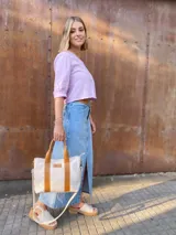 Bolso tipo tote de lona color crudo con detalles en cuero color marrón. Tiene doble asa corta de mano y correa larga de hombro.