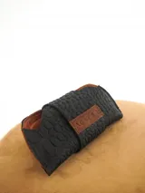 Estuche para lentes color borgoña con textura símil cocodrilo y cierre con broche a presión.
