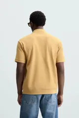 Polo azul marino de punto con textura acanalada vertical, corte regular fit, cuello solapa con abertura frontal y mangas cortas.