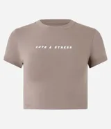 Remera color tostado de algodón y elastano, corte ajustado, cuello redondo y mangas cortas. Estampa frontal con la frase "Cute & Stress" en letras blancas.