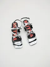 Sandalias de cuero charol color borgoña con tiras finas, taco cuadrado bajo y cierre con hebilla en el tobillo. Interior con estampado del logo de la marca en color naranja.