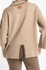 Sweater negro de tejido grueso con cuello alto acanalado. Presenta una franja decorativa en las mangas y el cuello en hilo marrón con brillo (lurex).