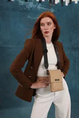 Bandolera tipo phone bag pequeña, color marrón claro, con correa de galón regulable. Tiene un compartimento principal y un bolsillo adicional con tapa.