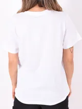 Remera blanca de algodón con cuello redondo y mangas cortas. Estampado frontal con imagen de palmeras y texto "Create New Horizons. Feeling the breeze over your skin".