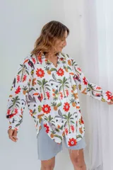 Camisa blanca con estampado de flores rojas, palmeras, piñas y tucanes.
