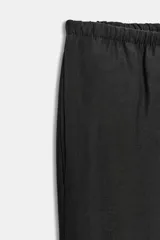 Pantalón negro de tejido fluido, tiro medio, cintura elástica ajustable con cordones y bolsillos laterales ocultos en la costura.