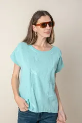 Blusa italiana color celeste con bordado de plumas al tono en el frente, confeccionada en lino y algodón.