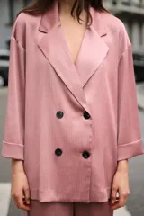 Blazer rosado de cuello solapa y manga tres cuartos con vuelta. Tejido con efecto arrugado y cierre cruzado con botones negros.